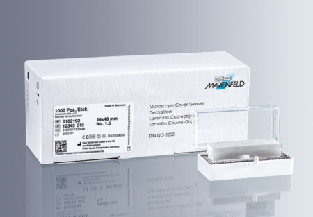 Box labeled "microscope cover glass no.1.5 (0.16 - 0.19mm)" with barcode and specs next to a small container of microscope cover glasses, all set against a gray background.