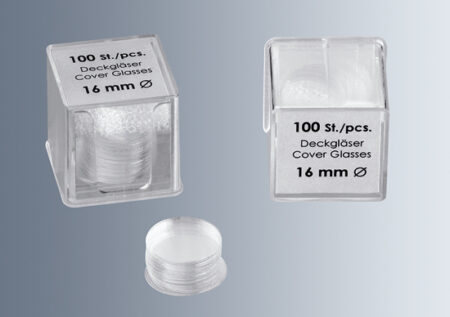 Two transparent plastic boxes labeled "100 St./pcs. microscope cover glass no.1 thickness (0.13 - 0.16mm) 16 mm" contain stacks of round cover glasses.
