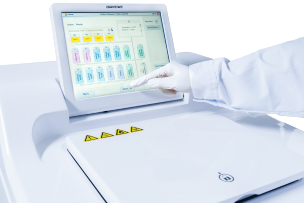 A person is pointing at a computer screen displaying the HP300 Automatic Tissue Processor, maximum 300 Cassettes, 150 Cassettes per Basket.