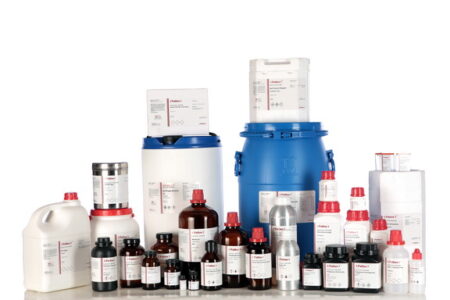 A variety of laboratory containers, including bottles labeled "sodium chloride 99.5% AR," as well as drums and boxes, are arranged on a white background.