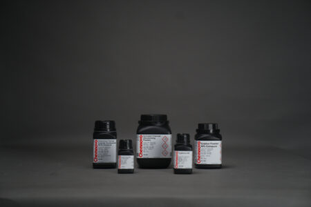 Five black plastic chemical bottles of various sizes are arranged on a gray surface against a dark gray background. Labels are visible but not fully legible.