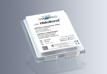 A stack of HistoBond®+S Microscope Slides, White, 90° ground edge with clipped corners (20x100/carton) rests in a clear plastic container against a light blue background.