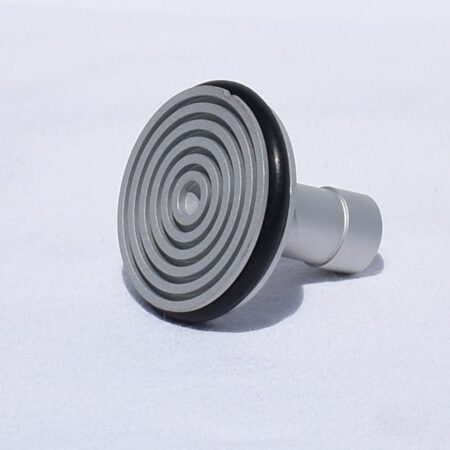 A cryostat specimen chuck/disk featuring concentric circular grooves and a black rubber ring is shown on a plain white background.