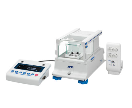 A laboratory analytical balance with a digital display unit and a remote control positioned beside it, all on a white background.