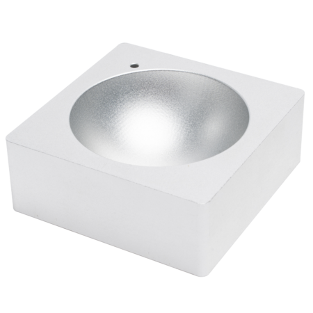 A square, silver metallic object with a circular, concave indentation in the center and a small hole near one corner.