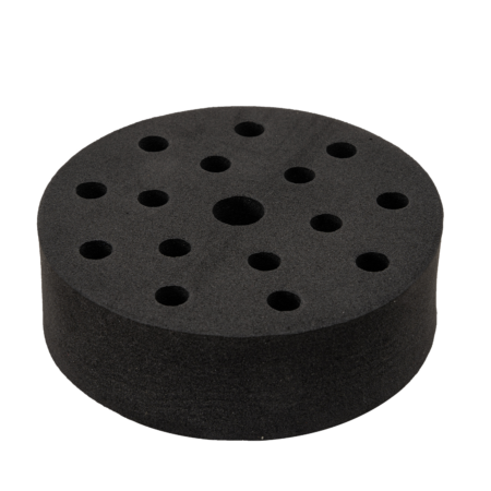 A round black foam disk with multiple holes of varying sizes arranged across its surface.