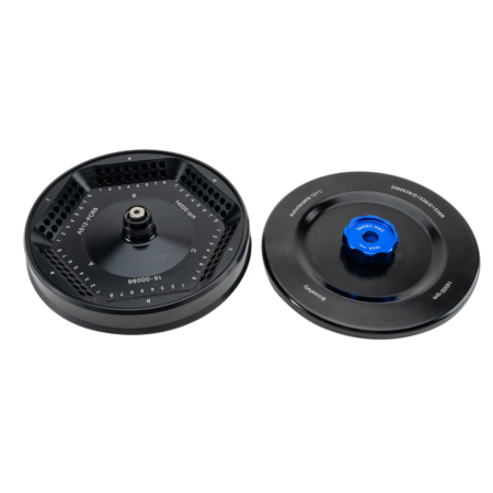 Two black circular film developing tanks with perforated inner parts, one with a blue-capped center, both components shown on a white background.