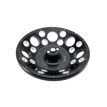 A black circular fly fishing reel spool with numbered perforations around the edge, viewed from above on a white background.