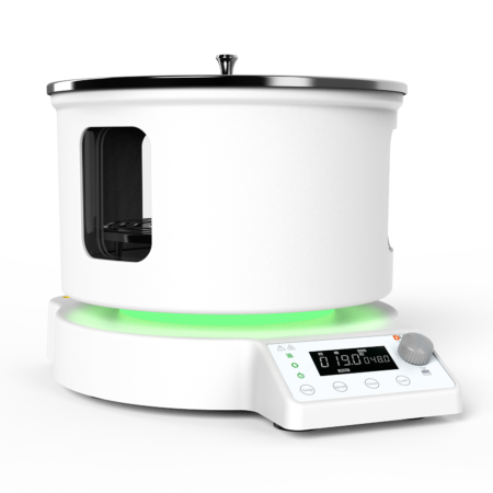 A modern white laboratory heating device with a digital display, control knob, and windowed cylindrical chamber on top, set against a plain background.